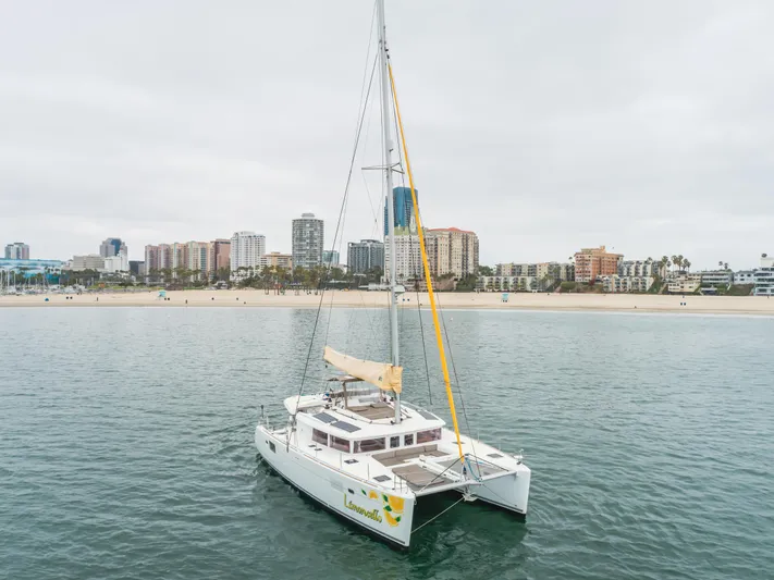 Limoncello Yacht Photos Pics Lagoon 450F catamaran sailing near a city shoreline, 2016 model.