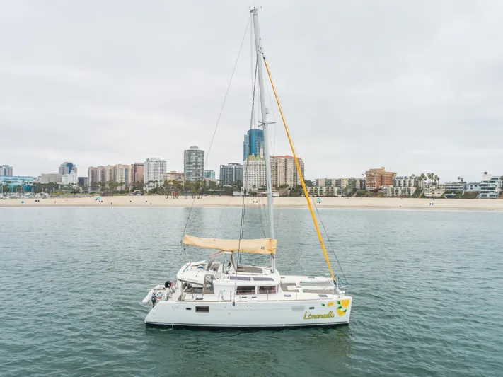 Limoncello Yacht Photos Pics 2016 Lagoon 450F catamaran sailing near a city shoreline with buildings in the background.