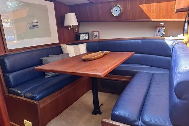 Arete Yacht Photos Pics 1988 Viking 45 Convertible yacht interior with blue leather seating and wooden table.