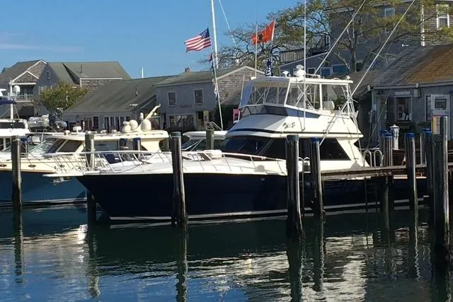 Arete Yacht Photos Pics 1988 Viking 45 Convertible yacht docked at a marina with flags and waterfront buildings.