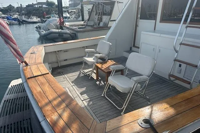 Arete Yacht Photos Pics 1988 Viking 45 Convertible yacht deck with chairs and table, docked in a marina.