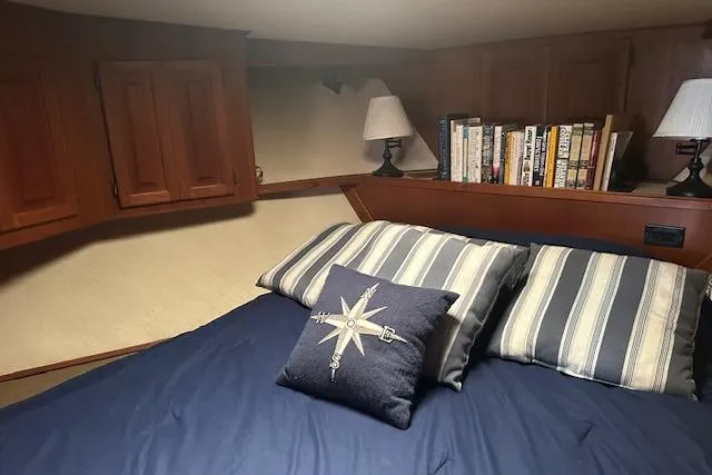 Arete Yacht Photos Pics Cozy cabin interior of 1988 Viking 45 Convertible with bed, pillows, and bookshelf.