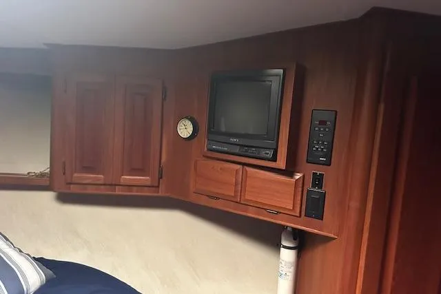 Arete Yacht Photos Pics 1988 Viking 45 Convertible cabin interior with TV, clock, and wooden cabinets.