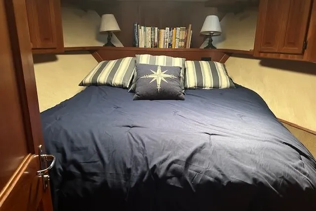 Arete Yacht Photos Pics Cozy bedroom in 1988 Viking 45 Convertible yacht with nautical-themed bedding and bookshelves.