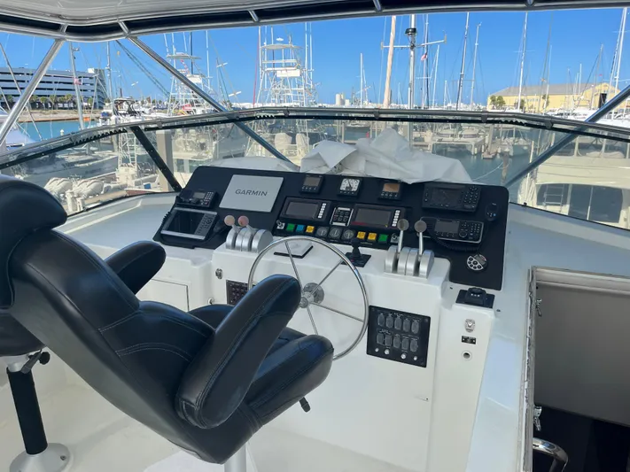 Final Kiwi Yacht Photos Pics Helm of 1995 Hatteras 74 Cockpit Motor Yacht with black captain's chair and control panel.