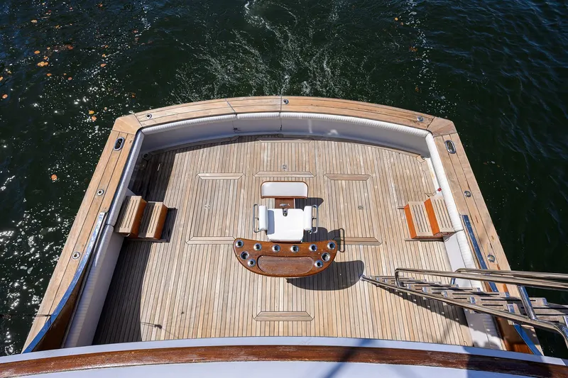  Yacht Photos Pics 1985 Feadship Yacht Fisherman deck with wooden flooring and fishing chair, overlooking water.