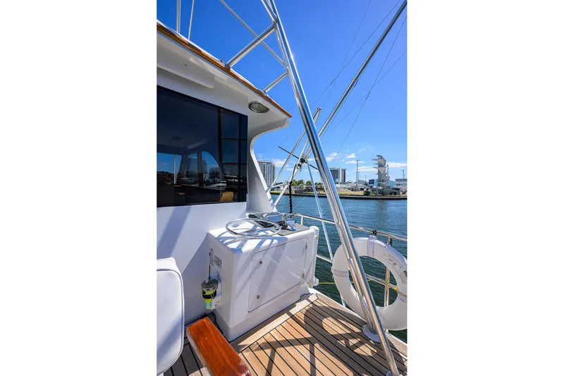  Yacht Photos Pics 1985 Feadship Yacht Fisherman deck with steering wheel, overlooking marina and cityscape.