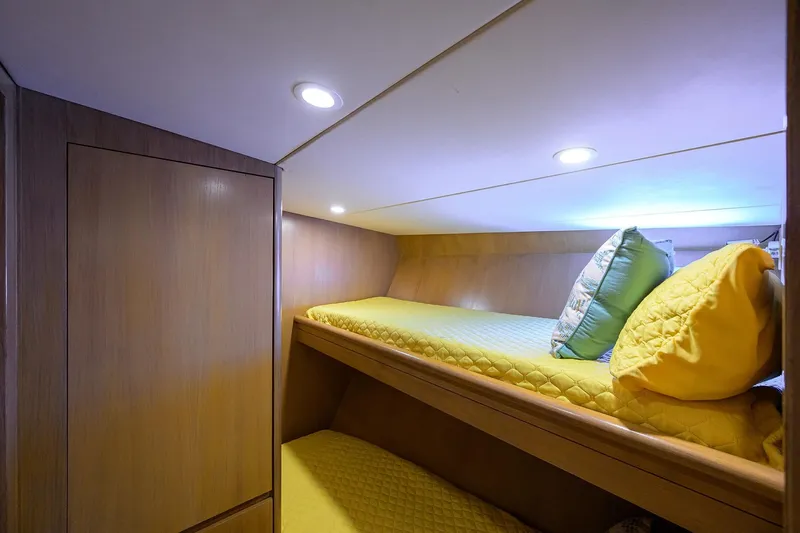  Yacht Photos Pics Cozy cabin with bunk beds on 1985 Feadship Yacht Fisherman, featuring yellow bedding and wood paneling.