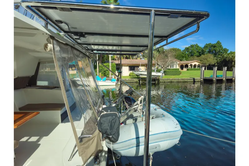 Waterlilly Yacht Photos Pics 2017 Fountaine Pajot Lucia 40 catamaran with dinghy, docked by waterfront property.