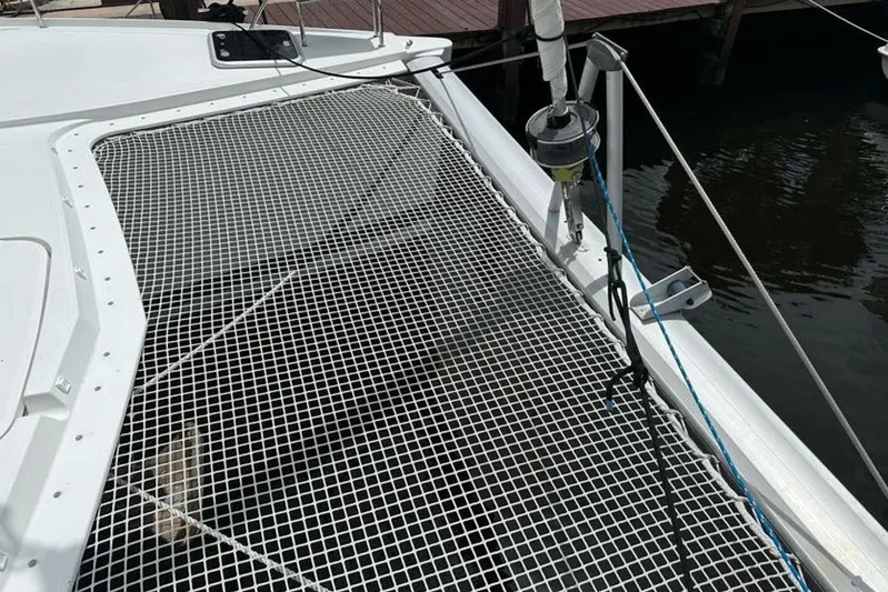 Waterlilly Yacht Photos Pics 2017 Fountaine Pajot Lucia 40 catamaran with netting on deck, docked by water.