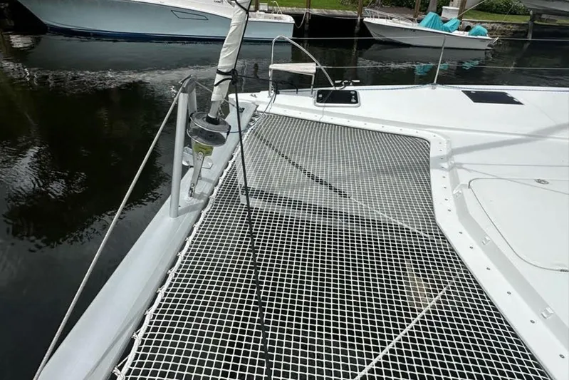Waterlilly Yacht Photos Pics 2017 Fountaine Pajot Lucia 40 catamaran with netted deck, docked by the water.