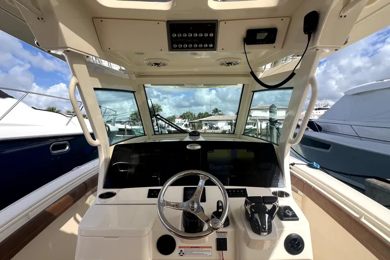 Bachita Yacht Photos Pics 2023 Scout 355 LXF boat helm with steering wheel and controls, docked at marina.