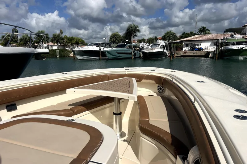Bachita Yacht Photos Pics 2023 Scout 355 LXF boat interior with seating and table, docked in a marina.