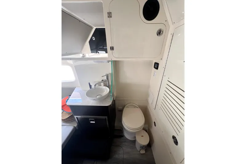 Bachita Yacht Photos Pics 2023 Scout 355 LXF boat interior bathroom with sink, toilet, and storage cabinets.