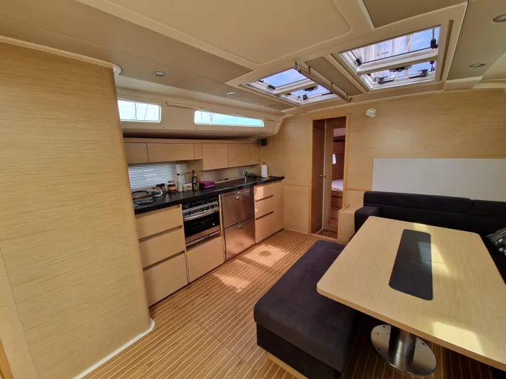  Yacht Photos Pics 2020 Hanse 508 yacht interior with modern kitchen and dining area, featuring skylights and wood finish.