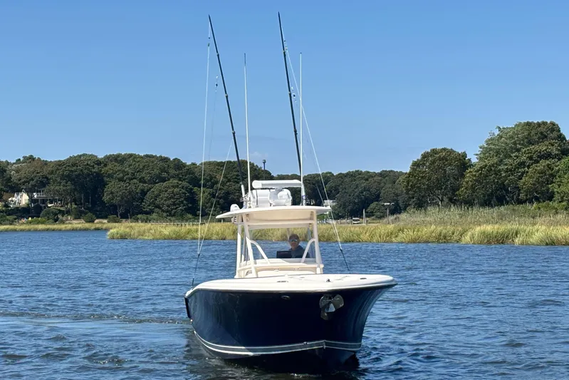  Yacht Photos Pics 2014 Pursuit C 310 Center Console boat on a scenic waterway with lush greenery.