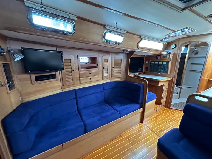 Innisfree Yacht Photos Pics Interior of 1994 Sabre 425 yacht with blue seating, wood paneling, and mounted TV.