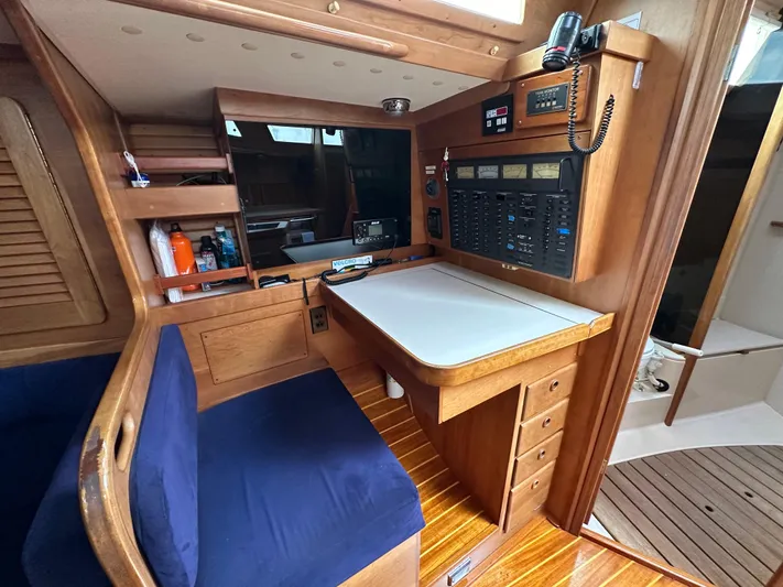 Innisfree Yacht Photos Pics Navigation station inside 1994 Sabre SABRE 425 sailboat with wooden cabinetry and blue seating.