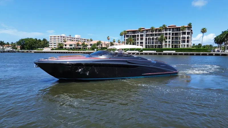 Lady D Yacht Photos Pics 2015 Riva Rivarama Super yacht cruising on a sunny day near waterfront buildings.
