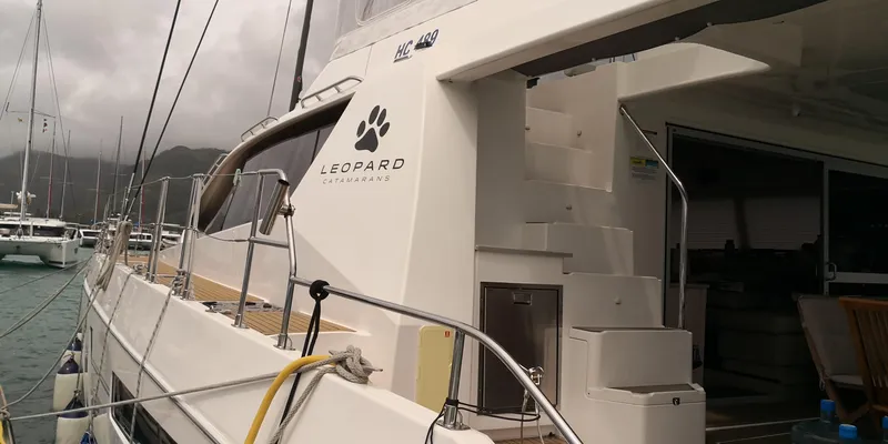 Between Yacht Photos Pics 2018 Leopard 58 yacht docked, showcasing sleek design and spacious deck area.