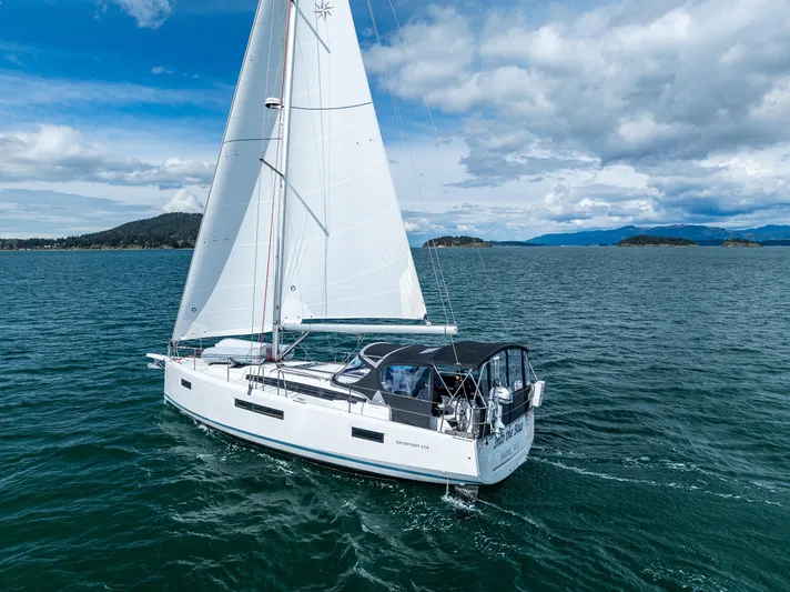 Into The Blue Yacht Photos Pics 2022 Jeanneau Sun Odyssey 410 sailing on open water under a cloudy sky.