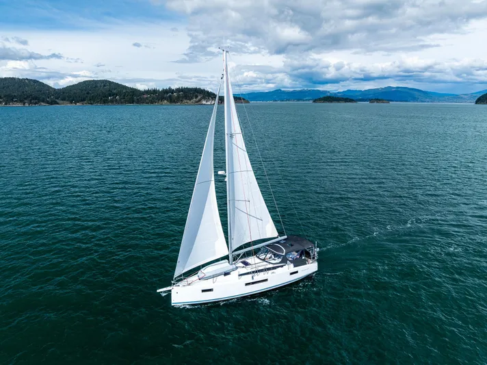 Into The Blue Yacht Photos Pics Sailing yacht Jeanneau Sun Odyssey 410, 2022 model, cruising on open water under cloudy skies.