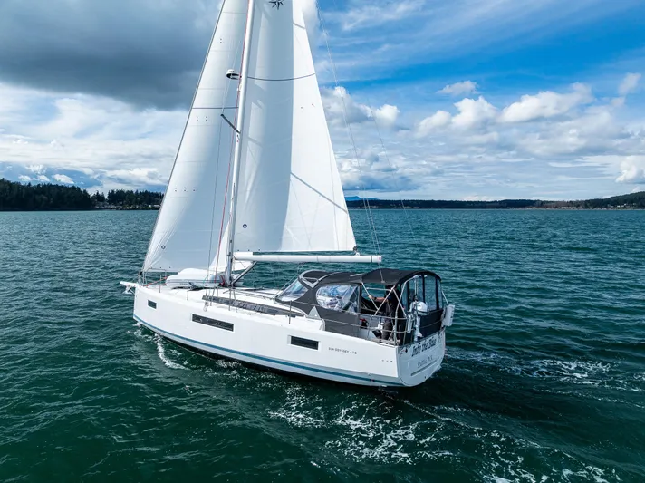 Into The Blue Yacht Photos Pics 2022 Jeanneau Sun Odyssey 410 sailing on open water under a cloudy sky.