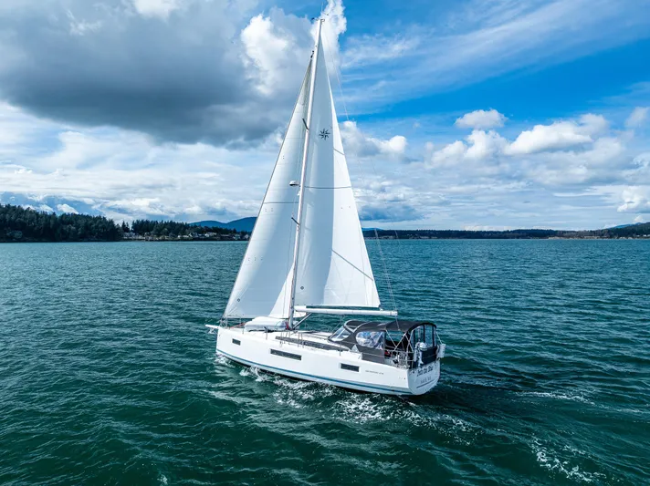Into The Blue Yacht Photos Pics 2022 Jeanneau Sun Odyssey 410 sailing on a serene, blue ocean under a partly cloudy sky.
