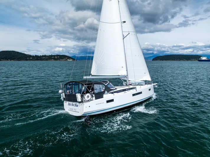 Into The Blue Yacht Photos Pics 2022 Jeanneau Sun Odyssey 410 sailing on open water under cloudy skies.