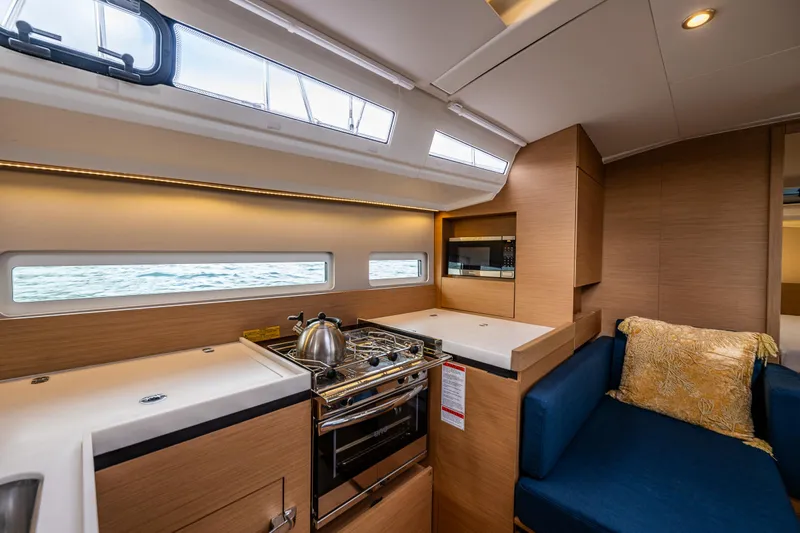 Into The Blue Yacht Photos Pics Modern interior of 2022 Jeanneau Sun Odyssey 410 yacht with kitchen and seating area.