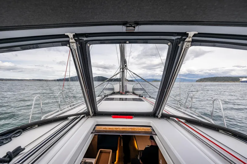 Into The Blue Yacht Photos Pics 2022 Jeanneau Sun Odyssey 410 sailboat deck view with open hatch and scenic ocean backdrop.