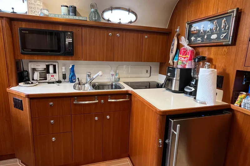 Summah Sled Yacht Photos Pics 1999 Tiara Yachts 4000 Express kitchen with wood cabinetry, microwave, and sink.