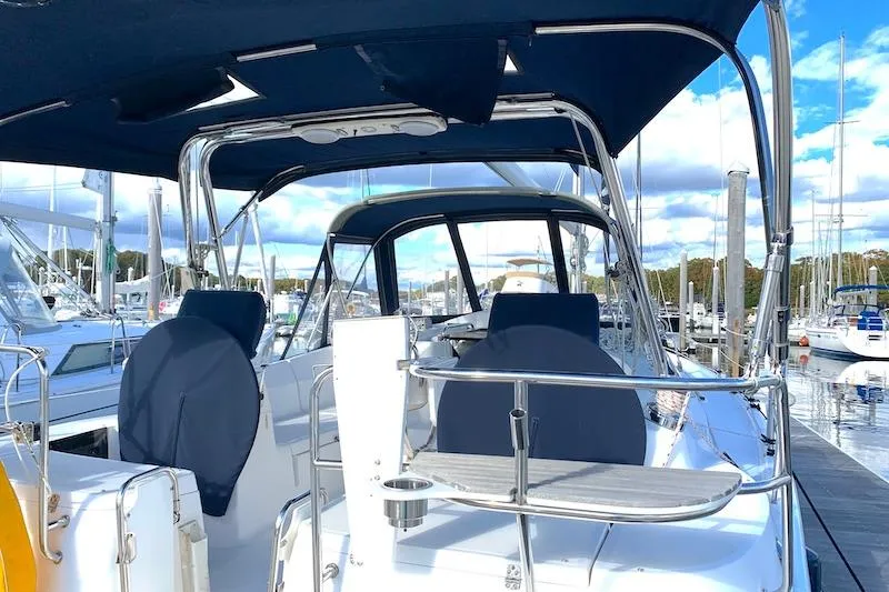 Sweet & Salty Yacht Photos Pics Sailboat cockpit view of 2011 Hunter 39 at marina, featuring covered seating and blue canopy.