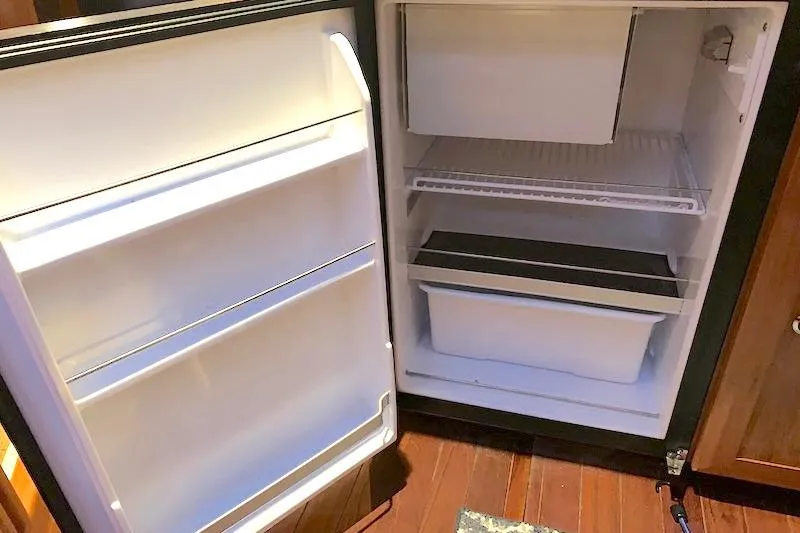 Sweet & Salty Yacht Photos Pics Open refrigerator in a 2011 Hunter 39 yacht, showing empty shelves and compartments.