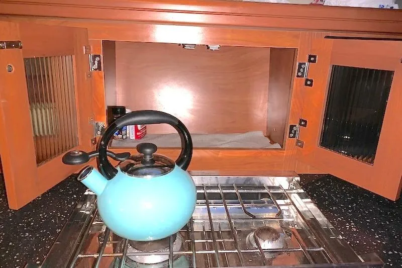 Sweet & Salty Yacht Photos Pics Blue kettle on stove in Hunter 39, 2011 model, with open wooden cabinets above.