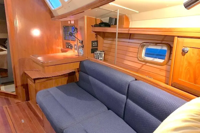 Sweet & Salty Yacht Photos Pics Interior of 2011 Hunter 39 sailboat with wooden paneling and blue sofa.