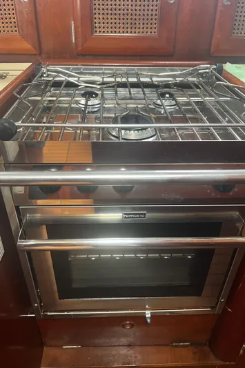 Chivalry Yacht Photos Pics Beneteau 461 2000 yacht kitchen with stove and oven, featuring wooden cabinetry.