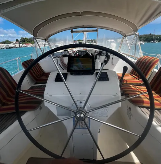 Chivalry Yacht Photos Pics Steering wheel of a 2000 Beneteau 461 sailboat with striped seating and ocean view.