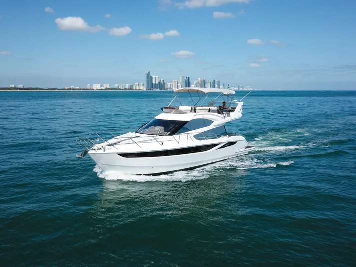 Yacht Photos Pics 2016 Galeon 420 Fly yacht cruising on blue ocean with city skyline in background.