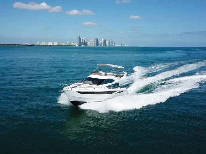  Yacht Photos Pics 2016 Galeon 420 Fly yacht cruising on open water with city skyline in background.