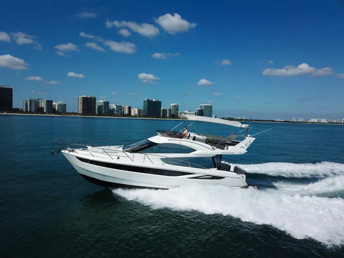  Yacht Photos Pics 2016 Galeon 420 Fly yacht cruising on open water, city skyline in background.
