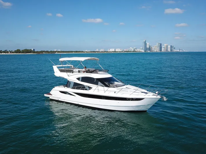  Yacht Photos Pics 2016 Galeon 420 Fly yacht cruising on blue ocean near city skyline.