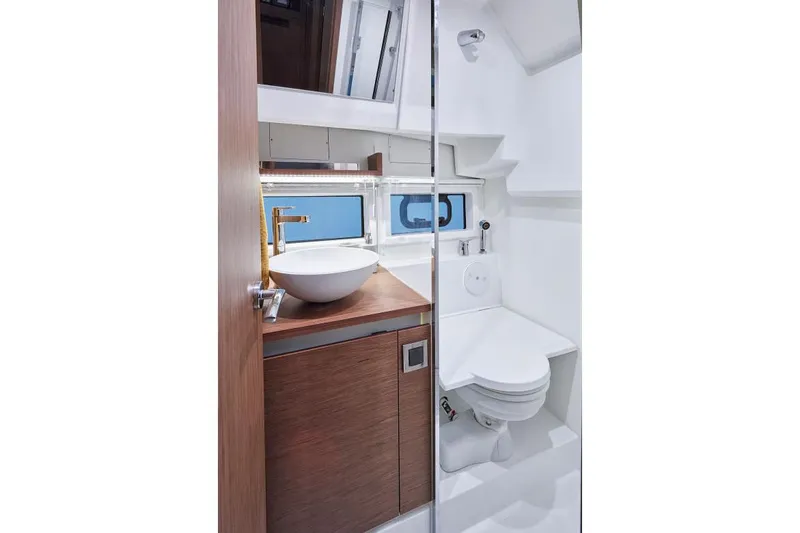  Yacht Photos Pics 2019 Jeanneau NC 33 yacht bathroom with modern sink, toilet, and wooden cabinetry.