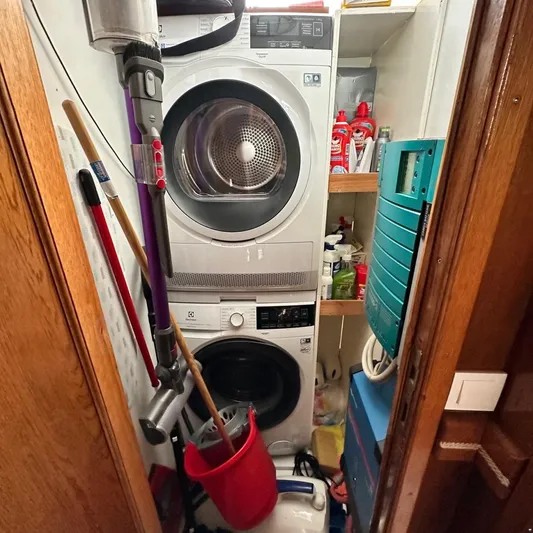  Yacht Photos Pics Laundry room on Viking Marin Caicco 1994 with stacked washer, dryer, and cleaning supplies.
