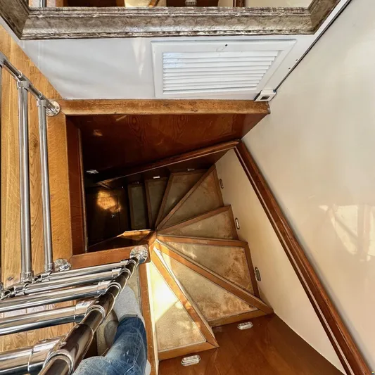  Yacht Photos Pics Spiral staircase inside 1994 Viking Marin Caicco yacht, featuring wooden steps and metal railing.