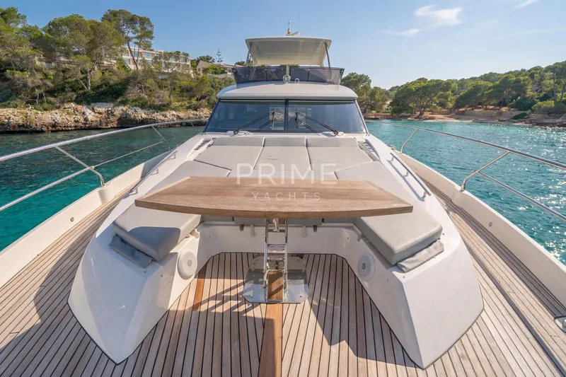 One Step Closer Yacht Photos Pics Luxurious 2024 Prestige 590 yacht deck with seating, table, and scenic coastal view.