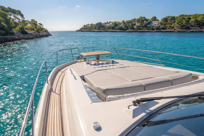 One Step Closer Yacht Photos Pics 2024 Prestige 590 yacht cruising in a serene, turquoise bay with lush greenery.