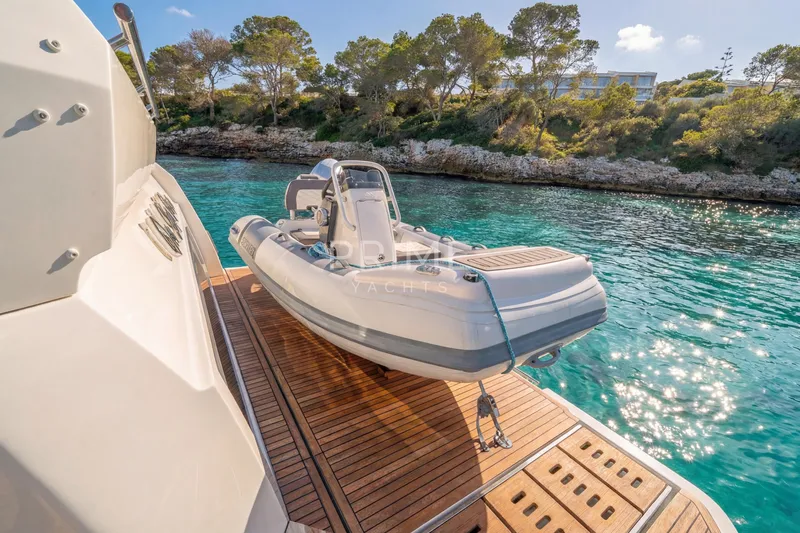 One Step Closer Yacht Photos Pics 2024 Prestige 590 yacht with tender on deck, docked in scenic coastal waters.