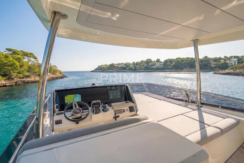 One Step Closer Yacht Photos Pics 2024 Prestige 590 yacht helm with scenic coastal view, featuring modern navigation equipment.