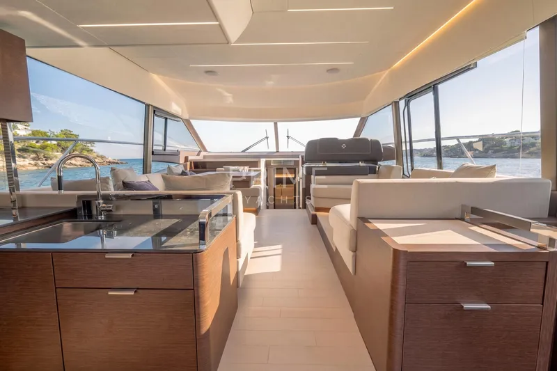 One Step Closer Yacht Photos Pics Luxurious interior of 2024 Prestige 590 yacht with modern kitchen and seating area.